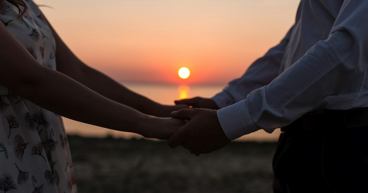 Silhouettes of a couple holding hands at sunset